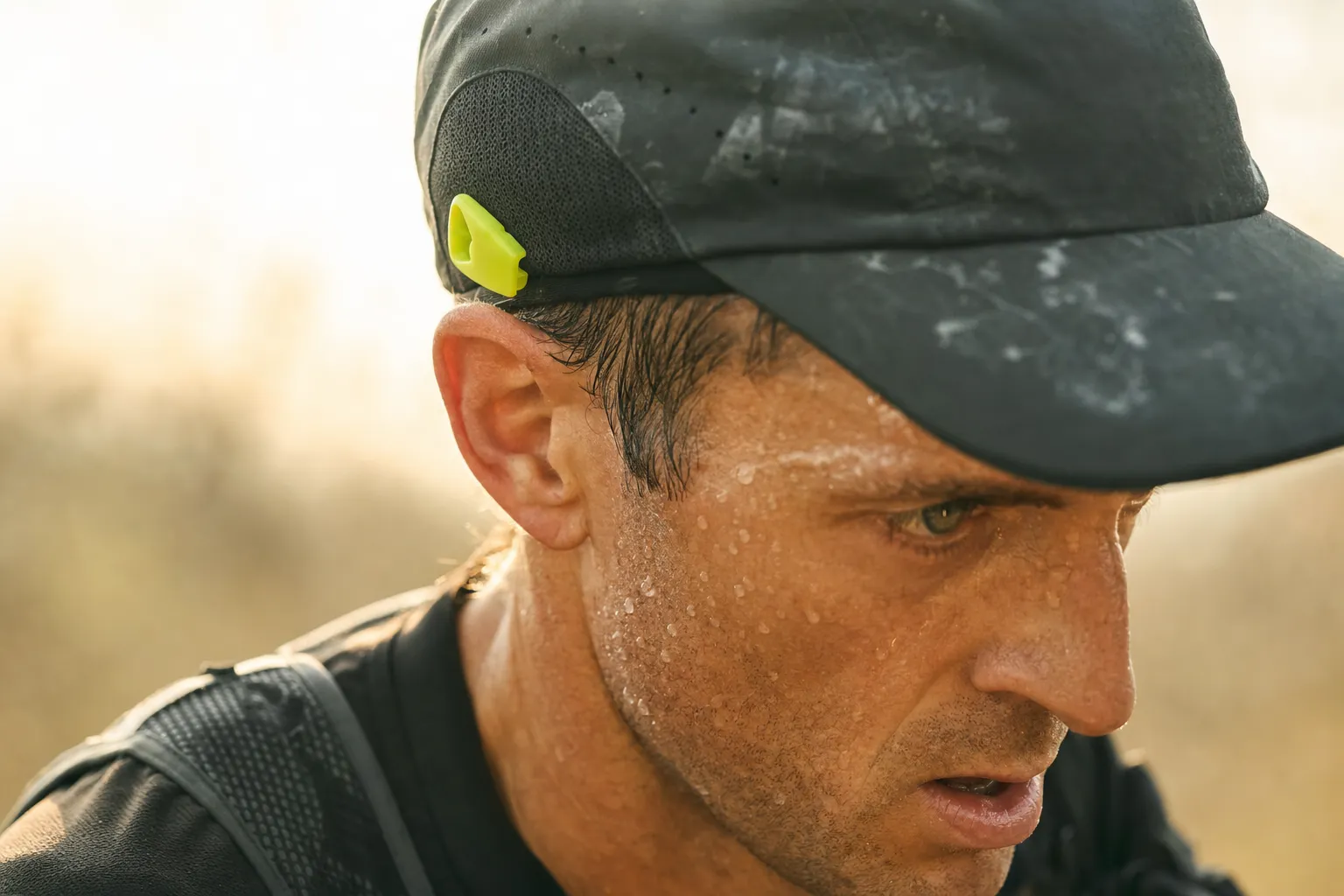 Gros plan d'un coureur en sueur, traces de sel sur la casquette.